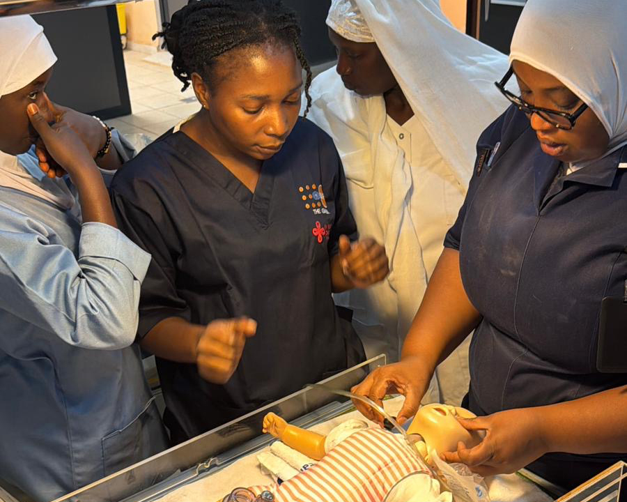 Lokale zorgverleners oefenen tijdens een medische training met een babypop als onderdeel van het geboortezorgproject in Gambia.